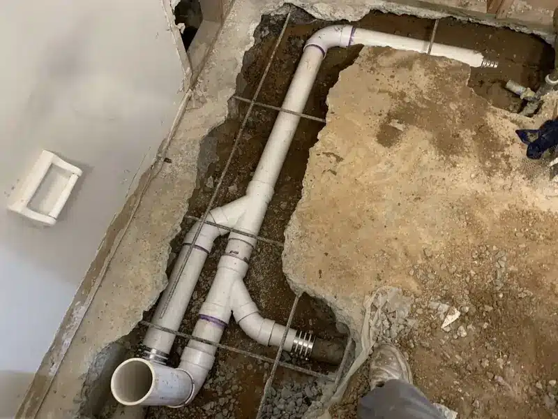 Slab leak repair showing exposed plumbing pipes beneath a concrete floor