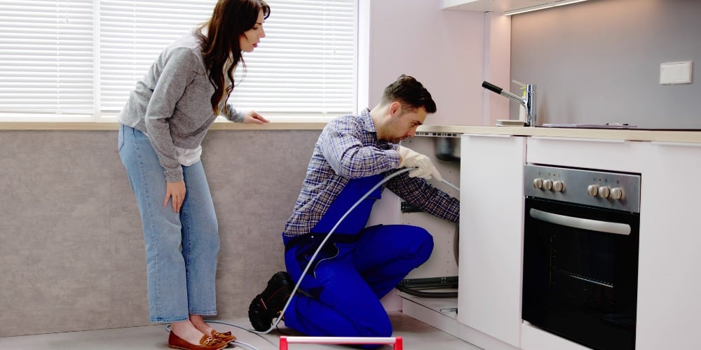 Plumber fixing kitchen sink plumbing