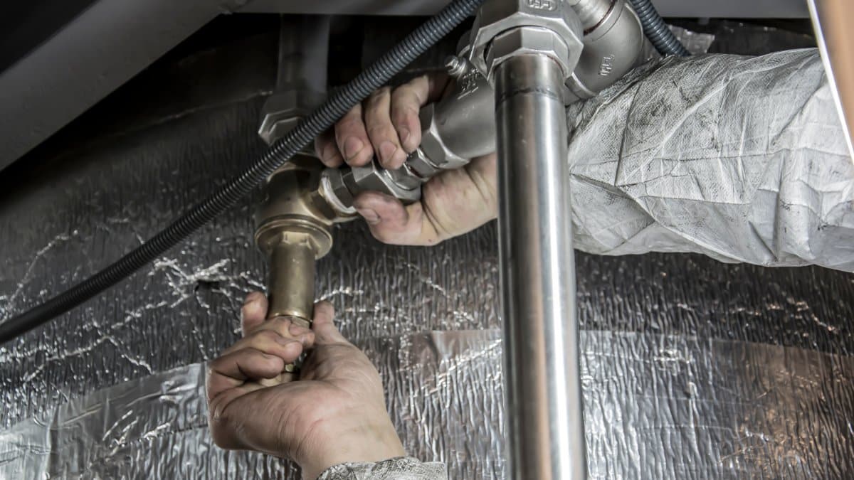 Plumber's hands installing steel pipes indoors