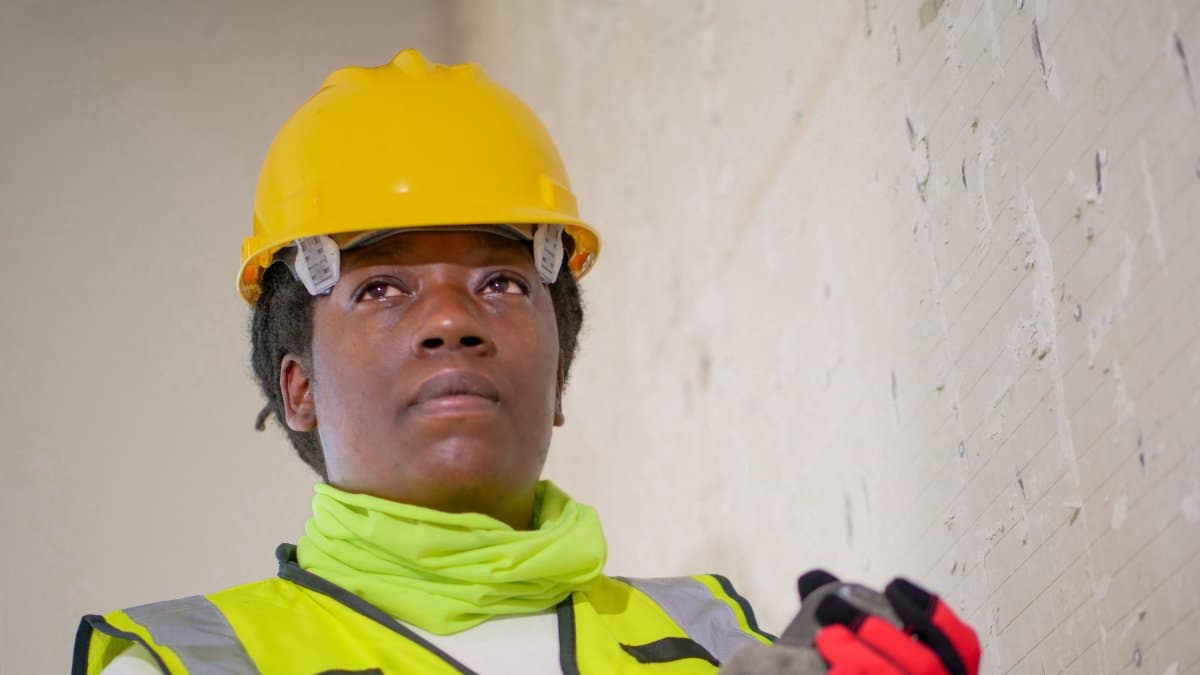 Female construction worker in safety gear holding a plumber's wrench indoors